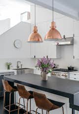 The kitchen is outfitted with a granite countertop and custom casework; the hardware is by Tom Kundig. Richard and his wife, Kristine, sourced the pendants from Craigslist, then had them plated in copper. The appliances are by Viking, and the bar stools are Real Good chairs by Blu Dot.