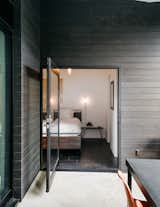 The patio is accessed from the master bedroom via a large pivot door. The bed and mirror are from Crate and Barrel; the pendant is from Droog. The couple made the wall sconces themselves.