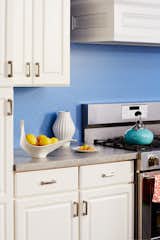 Rendered in sharp blue, the timeless motif of Greek Key is used as this kitchen's backsplash. The two-tone pattern is playful and modern against the more traditional white cabinets with molding and raised panels.
