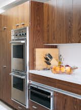 Kitchen, Wall Oven, Microwave, and Wood Cabinet In the kitchen, the couple added a skylight and replaced blue Formica counters with white quartz, but they kept the cabinetry installed in the 1980s and a vintage Thermador bread warmer.  Photo 5 of 12 in Pretty as a Picture
