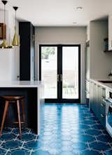 Kitchen, Engineered Quartz Counter, Cement Tile Floor, and Pendant Lighting Vintage lover Sarah Benson worked with local firm Bright Designlab to gently update her 1925 home in Portland, Oregon. In the kitchen, Moroccan cement tiles featuring a blue Hex Dot pattern by Popham Designs cover the floor.  Photo 6 of 7 in Ŕä from A 1925 Portland Home Is a Rad Mashup of 20th-Century Styles