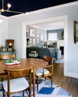 A mix of vintage and modern pieces furnish the home, including a table by Arne Vodder for George Tanier, an IKEA rug, and a Lambert &amp; Fils chandelier in the dining room. A bar cart from her grandmother is one of Sarah’s most prized possessions. The ceiling color is Benjamin Moore Marine Blue.