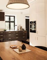 Kitchen, Pendant Lighting, Wood Counter, White Cabinet, and Wood Cabinet Lisette Bernhoft of Design by Us planned the kitchen. The smoked oak cabinets are topped with lava stone. The pulls are brass.  Photo 2 of 21 in Modern Danish Homes We Love by Aileen Kwun from Urban Renewal