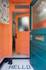 The vestibule is painted in Benjamin Moore’s coral-hued Hot Spice and covered in a Cuban-inspired floral wallpaper by fashion designer Matthew Williamson for Osborne &amp; Little.