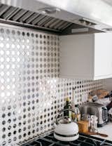 In an otherwise mostly white kitchen, the mirrored concrete tile backsplash introduces an unexpected element. The floor is also covered with the same tile from Mission Tile West, giving a fun, almost disco-like vibe to the space.