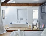 Prolific Dutch designer Danny Venlet rebuilds his roost in Brussels.&nbsp;A spare layout marks the master suite on the third floor. The rectangular KOS bathtub, integrated into an elevated plywood platform, pairs with Gert Van Der Vloet’s Cut Low lounge in Corian. The couple used elements of a photo they took of one of Venlet’s designs to create the graphic wall covering.