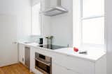 Kitchen, Cooktops, Range Hood, Range, Dishwasher, White Cabinet, Undermount Sink, and Medium Hardwood Floor The space-saving appliances are all from Bosch’s 500 and 800 series.  Photos from This 390-Square-Foot Renovation Is Compact Yet Comfortable in Greenwich Village
