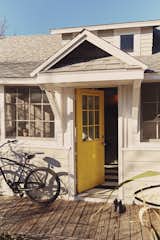The door to the front porch, painted in Bright Yellow by Benjamin Moore, is inspired by the island’s local flora.   Photo 1 of 25 in 25 Playful Homes Splashed With Vibrant Pops of Yellow