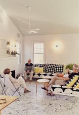 Residents Ann and Tony Spagnola sit with their architects, Peter Stamberg and Paul Aferiat, in front of the whitewashed brick fireplace in the living room. A vintage Butterfly chair joins custom sofas designed by the architects. Coffee tables by Alvar Aalto for Artek and pillows by Marimekko create a clean, Finnish-inflected environment.