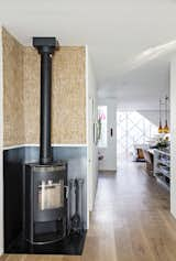 Upcycled Kirei wall board pairs with a Rais Gabo stove in the original part of the house, which connects seamlessly  to the prefab addition.