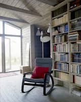 Near a Gent wood-burning stove by Thorma in the living area, an IKEA Poäng chair and ottoman provide a cozy spot for reading. Thanks to the passive design strategies utilized by Ovchinnikov, the house stays warm through the winter with only minimal heating required.