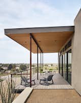 Outdoor, Back Yard, Side Yard, Front Yard, Large Patio, Porch, Deck, Wire Fences, Wall, and Metal Fences, Wall The east-facing facade opens to an outdoor deck, which is furnished with lounge chairs by Loll Designs.  Photo 4 of 6 in The Long Way Home