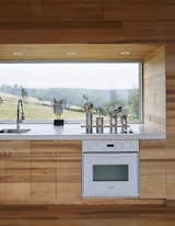 Kitchen, Drop In Sink, Wood Counter, Wood Cabinet, Cooktops, and Wall Oven The focal point of the home is the long Alumicor window that reveals the slope of the site.  Photo 4 of 12 in Sliding House from Lights Will Guide You Home