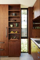 In the kitchen, an elongated window breaks the custom walnut cabinetry by Contour Woodworks.