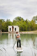 Cooper, 11,  paddleboards toward an outbuilding that contains a sauna.