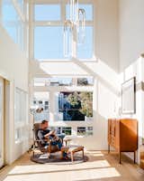 Tom and Kate own the top two  floors of the building. On the lower level, in the double-height foyer, Milo Baughman’s Recliner 74 is positioned beneath Rudi Double Loop pendants by Lukas Peet for Roll &amp; Hill. The floor lamp is a custom piece that De Angelis Designs adapted from a vintage salon hood dryer.