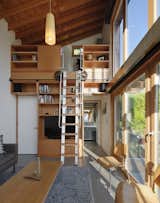 The double-height interior features an upper loft accessed by a custom wood-and-aluminum rolling ladder.