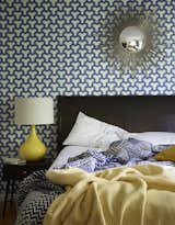 A sunburst mirror, which George bought on eBay, pops against patterned Antonina Vella wallpaper in the guest bedroom. The lamp is vintage.