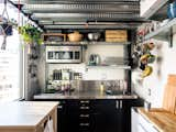 The kitchen, located behind the stairs and underneath Max’s bedroom, is all electric, with two burners, a rice cooker, a slow cooker, and a toaster oven. Max added industrial shelving and a butcher block. "Vertical storage," he notes, "is very important."