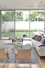 The living room is defined by large glass sliders by Fleetwood that open up to the backyard, allowing light to flood the downstairs space. The room features a Crosby sofa by West Elm, CH25 lounge chairs by Hans J. Wegner for Carl Hansen &amp; Son, and a OW 150 daybed by Ole Wanscher.