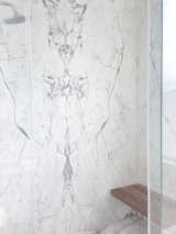The guest bathroom shower is complete with a Bianco Dolomiti Marble tile wall and a Studio Line Porcelain tile floor by Atlas Concorde.