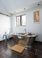 A freestanding copper tub, also by William Holland, sits exposed in a corner of the bathroom. The matching tile for the vanity and floor is by Marco Polo.