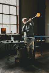 Designer Simon Pearce, shown at his factory in Windsor, Vermont, makes handblown glass the same way it’s been made for thousands of years, by melting the raw ingredients in huge ovens, then gathering the molten material onto iron blowpipes. A finished Westport footed glass sits on a nearby