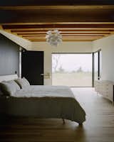 Bedroom, Dresser, Light Hardwood Floor, Shelves, Bed, and Pendant Lighting In the master bedroom, the ash bed was designed by Desai Chia  and fabricated by Gary Cheadle  of Woodbine; the dresser is by  George Nelson for Herman Miller. Panes by Western Windows  appear throughout the home.
-
Leelanau County, Michigan
Dwell Magazine : September / October 2017  Photos from Plagued Ash Trees Were Repurposed to Create This Charred Cedar–Clad Home on Lake Michigan