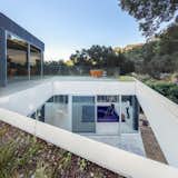 A bridge of steel grating leads to the garage and the entrance, both on the upper level. Sunlight funnels through an opening in the rooftop down to the living area. The orange hot tub is by ALFI.
-
Cupertino, California
Dwell Magazine : September / October 2017