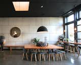 Dining Room, Chair, Table, Concrete Floor, Pendant Lighting, and Bench Large, communal tables, sound absorbing ceiling tiles, and street-side seating impart a cozy feel.  Photo 2 of 8 in An Australian Cafe Filled With Handcrafted Details Comes to Portland, Oregon
