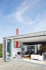 Outdoor and Wood Patio, Porch, Deck A home near Rye, England, opens onto a deck through a Sunflex door. The living room features a sofa by  Terence Woodgate, 620 chairs by Dieter Rams for Vitsœ, and an Oluce Atollo 239 lamp by Vico Magistretti.

Pett Level, England
Dwell Magazine : November / December 2017  Photo 2 of 14 in Fall in Love With This British Architect’s Colorful Weekend Retreat