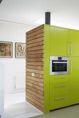 Kitchen, Colorful Cabinet, Painted Wood Floor, and Wall Oven The sides of the cabinets are clad in sweet chestnut; their faces are painted a custom shade of green by Dulux.

Pett Level, England
Dwell Magazine : November / December 2017  Photo 5 of 14 in Fall in Love With This British Architect’s Colorful Weekend Retreat