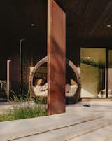 Rachel reclines in a daybed on the patio outside the master bedroom. In front, landscape architects Scatliff + Miller + Murray planted tall grasses on either side of the driveway to establish a prairie-like environment.

East St. Paul, Manitoba
Dwell Magazine : November / December 2017