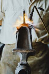 Shaping the Blade:  A special anvil called a “stake” is held in a T-shaped vice. With a torch in his left hand and a hammer in his right, Howard shapes the blade of the shovel around the bell-shaped stake.  Photo 12 of 14 in Meet a Seasoned Blacksmith Who Reveals His Art's Painstaking Process