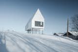 White concrete panel cladding and corrugated steel roof panels give this cabin a crisp, geometric form that almost melts into the landscape on bleary, snowy days.