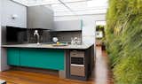Kitchen, Beverage Center, Medium Hardwood Floor, Colorful Cabinet, Refrigerator, and Wall Lighting  Photos from Living Green Walls Bring Jungle Vibes Into a Brazilian Apartment