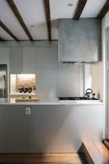 The kitchen range hood is framed in wood, wrapped with cement board, and parged with a thin layer of polished concrete. The sides of the Carrara-topped island are clad in anodized aluminum, as are the IKEA cabinets.
