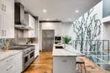Kitchen, Wall Oven, White Cabinet, Metal Backsplashe, Medium Hardwood Floor, Recessed Lighting, Refrigerator, Undermount Sink, Marble Counter, Range Hood, and Range  Photo 5 of 8 in East Division Street by Dwell