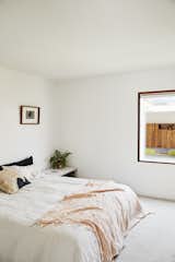 Bedroom, Bed, Night Stands, and Carpet Floor Grant painted the master bedroom and the rest of the interior Alabaster by Resene. For big jobs, like framing the walls, they relied on Langsford Construction.  Photo 9 of 17 in This DIY Home in New Zealand Doubles as a Coffee Spot and Art Gallery