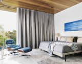 Bedroom, Bed, Table, Floor, Chair, Rug, and Terrazzo Drapes by Cush Cush Design offer privacy in the master bedroom. An Andy Moses painting hangs above the bed.  Bedroom Rug Table Terrazzo Photos from This House in Austin Has a Tree Growing Right Through It