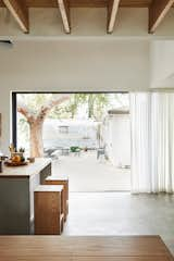 Dining Room, Table, Stools, Pendant Lighting, Concrete Floor, and Bar Sliders open to a deck and beyond to a 1960s Airstream once owned by sculptor Alma Allen in Joshua Tree. The couple use it for guests.  Photos from Explore the Japanese-Style Home of Two L.A. Tastemakers