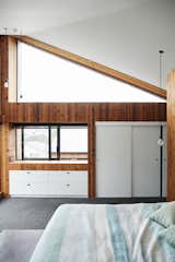 Bedroom, Dresser, Bed, Pendant Lighting, and Carpet Floor In the master bedroom the high triangular window is “excellent for stargazing,” says Rich.  Photos from This New Zealand Architect Created a House That Looks Like a Tiny Village