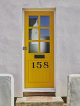 The window frames, side gate, and front door were brightened with custom shades from Johnstone’s Paint—a playful blue-yellow-orange color scheme that is carried throughout the house.