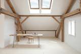 Sunlight streams into Reinhold and Verena’s loft through Velux skylights in the pitched roof. Reinhold fastened hairpin legs to an old table to create a desk, pairing it with a bentwood chair. The untreated spruce floorboards—many of which are a foot wide and 14 feet long—come from a stand of trees on the property and were milled on-site. The walls are coated in a custom lime-based paint.