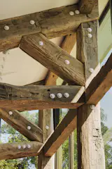 Working with Lancaster County Timber Frames and engineer John Schneider, the architects repurposed aged oak beams for the extensions; the new metal fasteners were painted white.