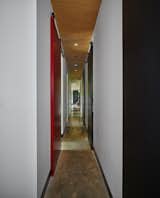 Black and red wooden panels supported by barn door tracks from Richard Wilcox elongate the narrow hallway connecting a series of bedrooms to the living area.
