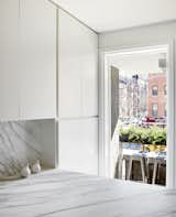 Kitchen, Marble Counter, Marble Backsplashe, and White Cabinet The kitchen counters and backsplashes are Calacatta Gold marble. The terrace barstools are Tolix Marais from Design Within Reach.  Photos from A Lush Wallcovering Brings the Feeling of Nature Into This Tiny New York Apartment