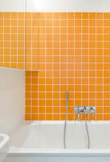 Bath time is never dull for the couple’s two young children, thanks to bright orange Interni tiles by Domus.