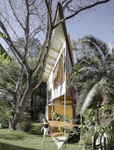 Outdoor, Shrubs, Wood Patio, Porch, Deck, Large Patio, Porch, Deck, Trees, Back Yard, and Grass The western wall of the treehouse is clad in metal to shade the structure from afternoon sun.  Photo 2 of 11 in This Triangular Tree House Adds Whimsy to a Backyard in Australia