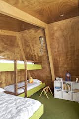 Kids Room, Storage, Carpet Floor, Bunks, Bedroom Room Type, and Bed Beneath the pitched roof, there’s a bedroom with custom bunks for visiting grandchildren.  Photos from This Bunker-Like Home in New Zealand Fights Back Against Howling Winds Off Lake Wanaka